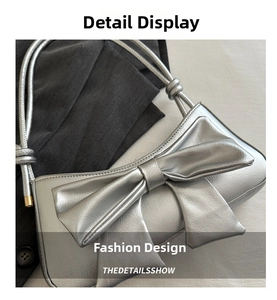 Close-up of silver faux leather shoulder bag with a large decorative bow detail