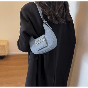 Detailopname van lichtblauwe denim halve maan tas met gouden geometrische metalen gesp