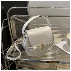 Detail of white chain saddle bag featuring gold buckle decor and detachable strap