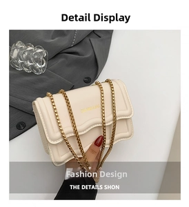 Detail of cream white leather bag with gold chain strap and wavy flap design