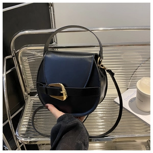 Detail of a black leather saddle bag with gold buckle on a stylish metal shelf