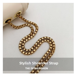 Detailed view of the gold square-link chain strap and metal grommets on a white bag
