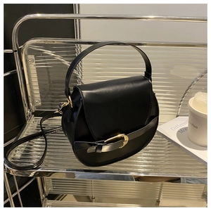 Detailed close-up of a black leather saddle bag with golden horseshoe metal buckle