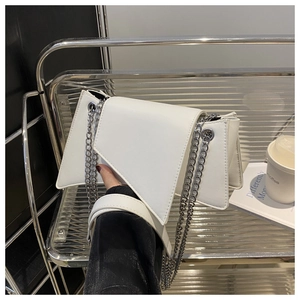 Détail d'un sac à bandoulière asymétrique en cuir blanc avec double chaîne argentée