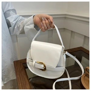 Detailed close-up of a white textured crossbody bag with a large gold buckle and slim strap