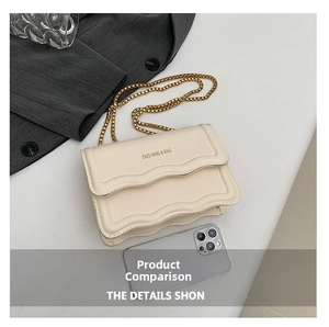 Detail of cream flap bag with scalloped edges, gold chain strap, and smartphone for scale