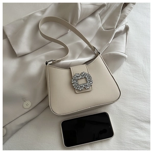 Detail of off-white leather underarm bag with crystal square buckle on a silk blazer