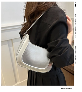 Detail of silver metallic hobo bag worn over shoulder on a black blazer jacket