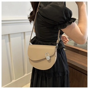 Khaki saddle bag detail showing asymmetrical flap and silver oval metal twist lock clasp