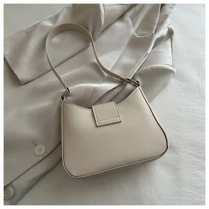 Detail of minimalist cream leather underarm bag on satin blazer for a high-end look