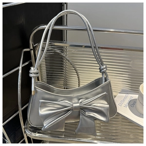 Close-up of a silver bow shoulder bag featuring metallic crocodile texture and fine straps