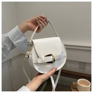 Detailed view of the white saddle bag with a large golden buckle and smooth PU leather finish