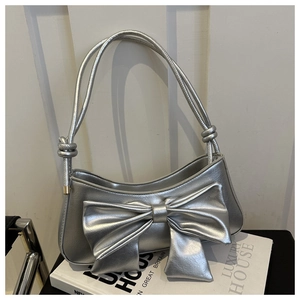 Detail of silver metallic leather handbag with a large decorative bow and knot handles