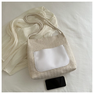 Detailed woven straw tote bag with a white leather pocket and soft rope shoulder strap