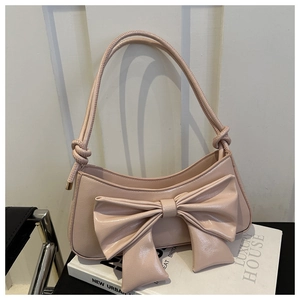 Detail of light pink glossy PU leather shoulder bag with large decorative bow accent