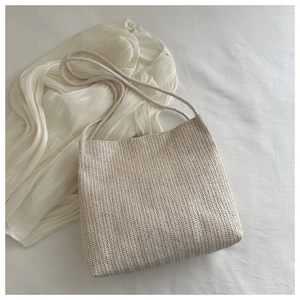Close-up of beige woven shoulder bag showing V-pattern texture and summer casual style