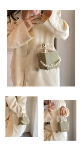 Detail of light green suede box bag featuring pearl handle and drawstring closure