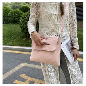 Pink crossbody bag with a cutout handle design and wrinkled texture in an outdoor setting