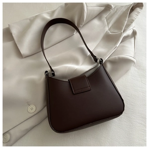 Detail of a deep brown leather underarm bag on a cream satin suit jacket with silver buckle