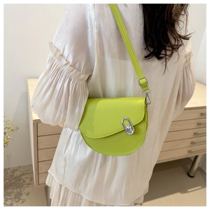 Detail view of a neon green saddle crossbody bag featuring a silver oval metal lock