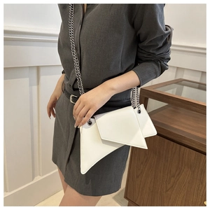 Détail d'un sac asymétrique en cuir blanc avec fine bandoulière en chaîne argentée