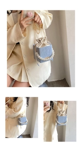 Detail of blue box bag featuring satin drawstring closure and large pearl handle strap