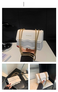 Detail view of white chain bag featuring a wavy flap edge and gold chunky chain strap
