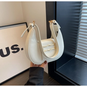 Detail van witte hobo tas met een gegolfde gouden metalen gesp en gladde leertextuur
