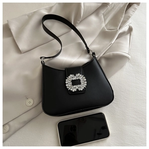 Detail of black leather underarm bag featuring a crystal sunflower buckle and slim strap