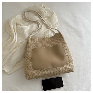 Flat lay of a beige woven tote bag with leather pocket and white rope handles
