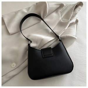 Detail of matte black underarm bag with crescent shape on white satin blazer
