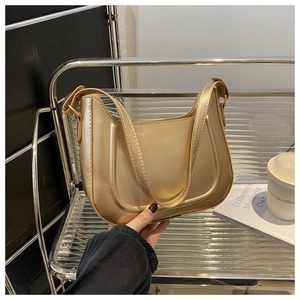 Detail shot of a champagne gold metallic shoulder bag with clean stitching and minimal style