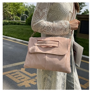 Close-up of pink pleated PU leather shoulder bag with metallic buckle and lace cardigan