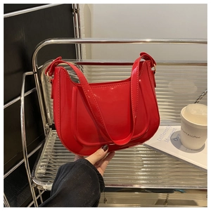 Detail of red patent leather baguette bag styled on a silver shelf with a coffee cup