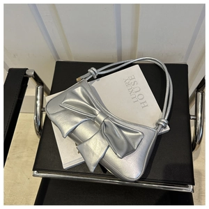 Detailed close-up of a silver metallic shoulder bag with a large decorative bow