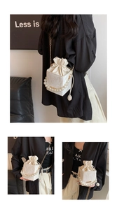 Detail of white textured bucket bag with pearl handle and golden chain strap
