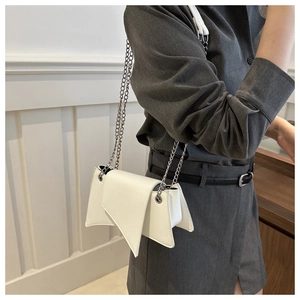 Close-up of a white asymmetric flap shoulder bag with silver metal chain straps