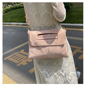 Détail du sac à bandoulière rose en similicuir texturé avec boucle dorée en métal