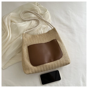 Close-up of beige woven straw tote bag featuring a contrast dark brown leather pocket