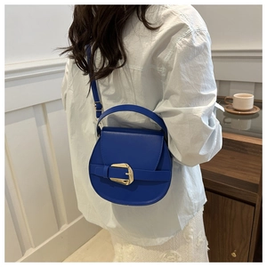 Close-up of royal blue saddle bag featuring a decorative oversized gold buckle and strap