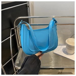Detail of sky blue patent leather crescent bag featuring a sleek zipper and smooth finish