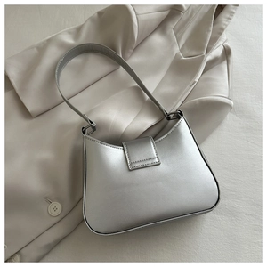 Detailed view of silver matte underarm bag on beige blazer showcasing minimalist design