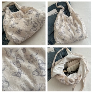 Detail view of large white bucket tote bag with feather texture and butterfly patterns