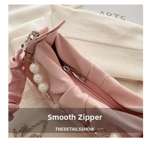 Detail of smooth silver zipper and elegant pearl chain on pink ruched crossbody bag