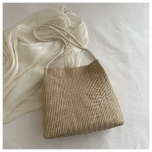 Close-up of beige woven straw tote bag with textured herringbone pattern and rope handles