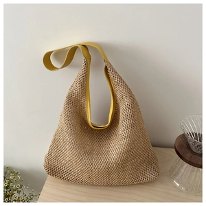Detail of woven straw tote bag featuring vibrant yellow leather straps and mesh texture