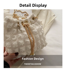 Detail of white bucket bag with popcorn texture, gold chain and pearl embellishment