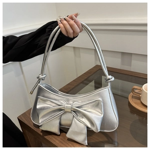 Close-up of metallic silver shoulder bag with large bow and crocodile texture