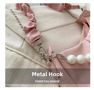Detail of pink pleated crescent bag with silver lobster clasp and white pearls