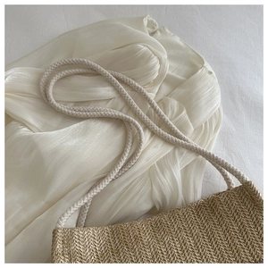 Detailed top view of a woven straw tote bag featuring white braided rope shoulder straps